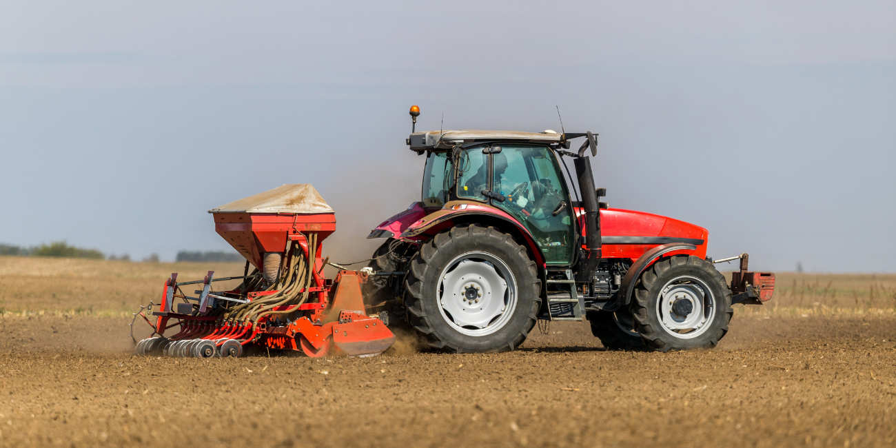 Red tractor mowing the field